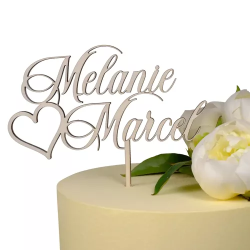 Cake Topper mit dem Schriftzug "Melanie Marcel" und einem Herz aus Holz auf einer beigen Torte mit Blumen