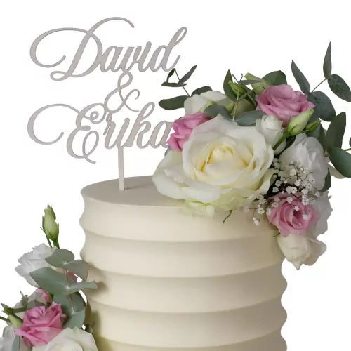 Cake Topper mit dem Schriftzug "David & Erika" aus Holz auf einer weißen Torte mit Blumen