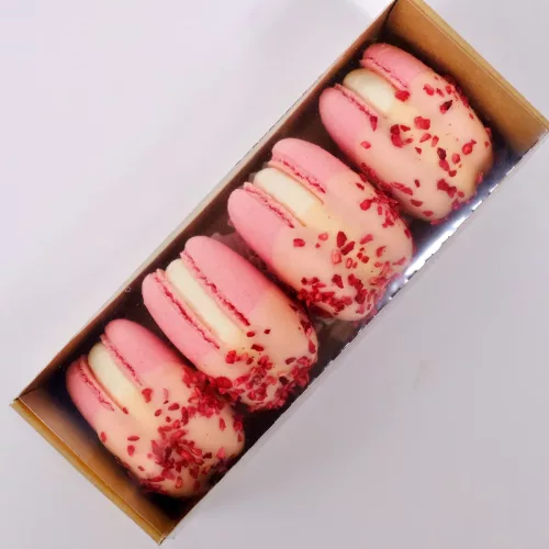 Eine braune Macaron Box aus Karton für vier Macarons mit Sichtfenster und vier rosanen Macarons in der Draufsicht