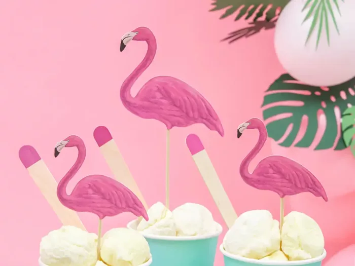 Drei Eisbecher mit Eis dekoriert mit drei Flamingo Cake Toppern vor rosanem Hintergrund