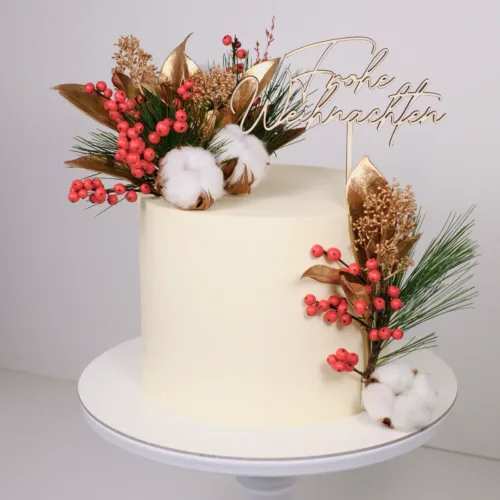 Weiße Torte weihnachtlich dekoriert mit einem Cake Topper aus Holz mit der Aufschrift Frohe Weihnachten