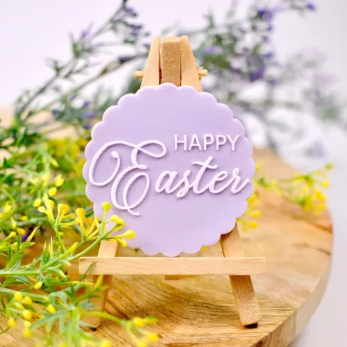 Ein runder Keks mit Vignettenform in Lila mit gestempeltem Schriftzug "Happy Easter" auf einer kleinen Staffelei