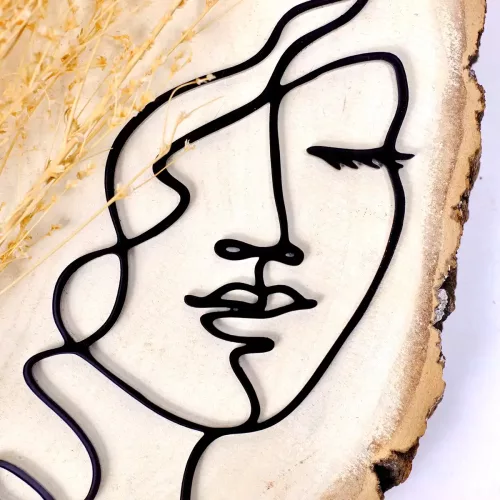 Nahaufnahme von einem Cake Topper mit Line Art der Silhouette des Gesichts einer Frau aus schwarzem Acryl auf dekorierter Holzplatte