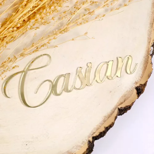 Personalisierter Cake Topper mit der Aufschrift "Casian" in geschwungener, Schrift aus goldenem Acryl auf einer Holzplatte