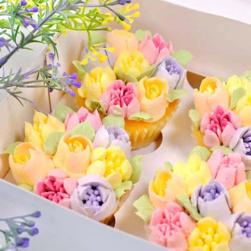 Nahaufnahme einer weißen Cupcake Box mit Cupcakes mit Blumen Buttercreme