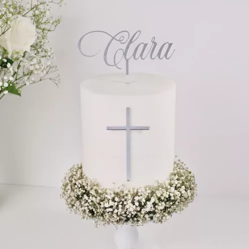 Aufnahme eines Cake Toppers aus silber Acryl mit dem Schriftzug "Clara" auf einer weißen, dekorierten Torte mit silbernen Kreuz