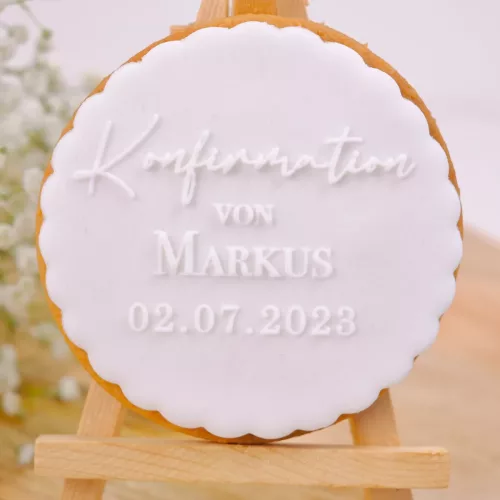 Weißer Keks mit folgendem Schriftzug: "Konfirmation von Markus 02.07.2023" auf Staffelei