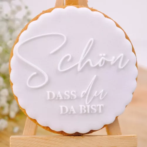 Weißer Keks mit folgendem Schriftzug: "Schön, dass du da bist" auf Staffelei