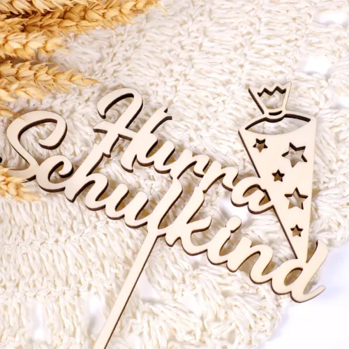 Cake Topper aus Holz mit der Aufschrift "Hurra Schulkind" und Schultüte auf einem gehäkeltem Tuch und Trockenblume