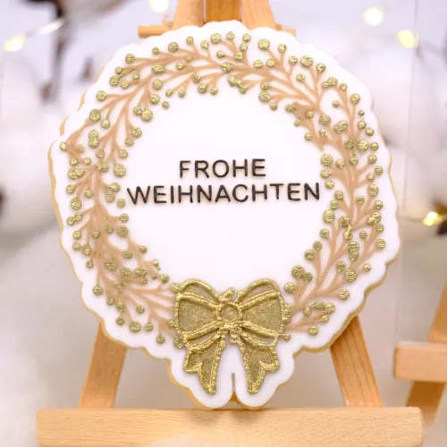 Goldener Keks mit Frohe Weihnachten Aufschrift auf einer Staffelei