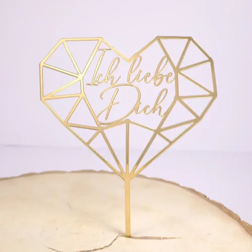 Goldener Cake Topper in Form eines Geoherzes mit der Aufschrift Ich liebe Dich auf einem Holz