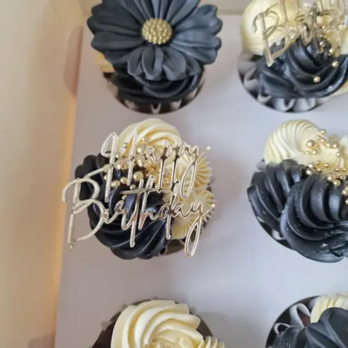 Schwarz weiße Cupcakes verziert mit einem goldenen Aufleger mit der Aufschrift Happy Birthday