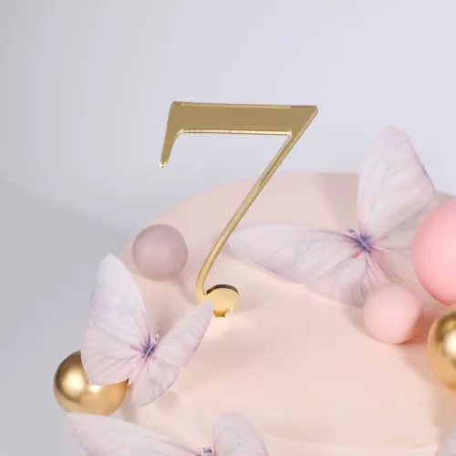 Goldener Cake Topper mit der Zahl 7 auf rosa Torte mit Schmetterlingen und Bubbles in Gold, Rosegold und Blush