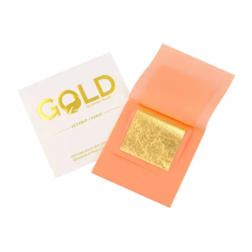 Ein orangenes Büchlein mit Blattgold in der Mitte und eine weiße Verpackung mit der Aufschrift Gold auf weißen Hintergrund