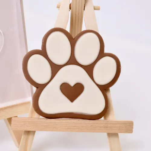 Beige-brauner Keks in Form einer Hundepfote auf einer Staffelei. Mit Herz in der Mitte.