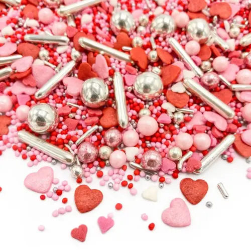 Verschiedene Streusel mit Liebes Motiven in den Farben rot, rosa, roségold, weiß und silber auf weißem Hintergrund