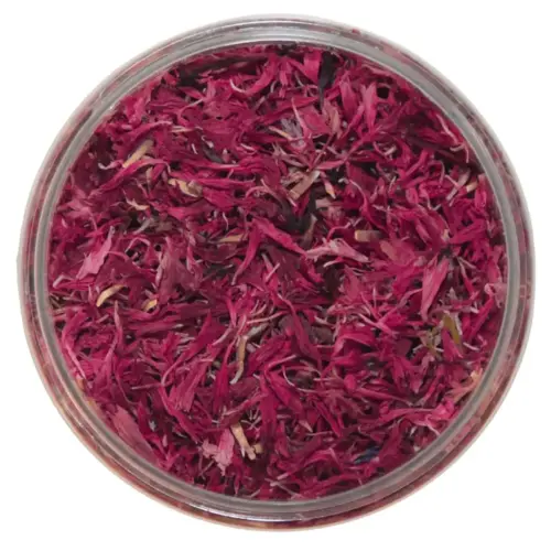 Getrocknete rote Kornblumenblütenblätter in einer geöffneten runden Dose, von oben.