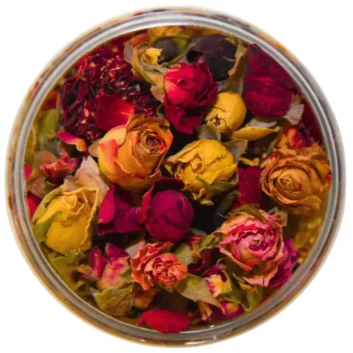 Getrocknete Rosenknospen in Rot, Rosa, Gelb und Orange mit grünen Kelchblättern in einer geöffneten runden Dose.
